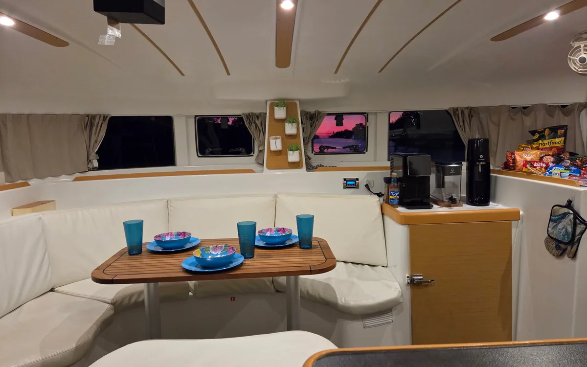 Majik’s salon end to end: wraparound cream seating, the dining table and the galley counter