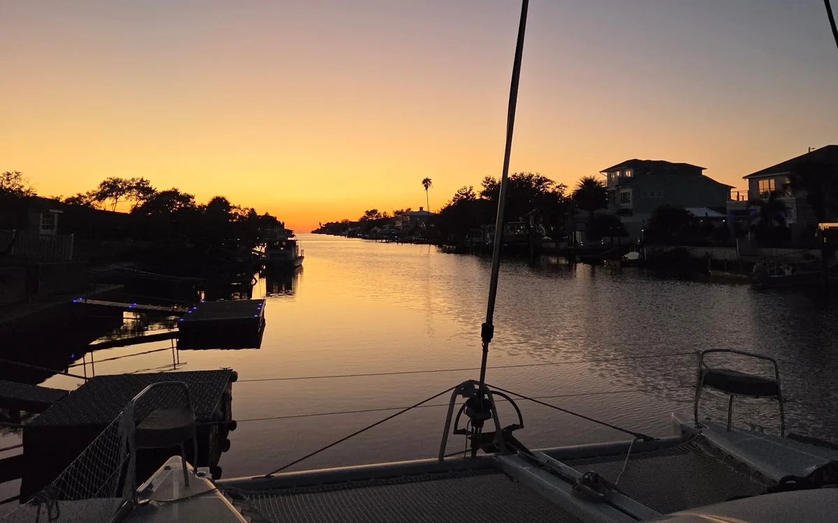 Sunset over the water seen from Majik’s bow, the trampoline and rigging in the foreground